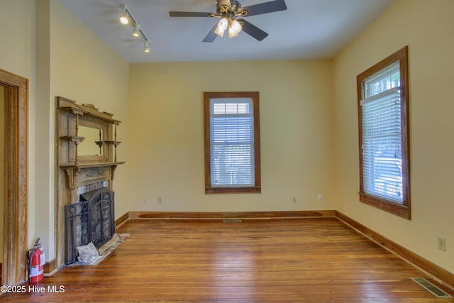 unfurnished living room featuring hardwood / wood-style floors, rail lighting, and ceiling fan