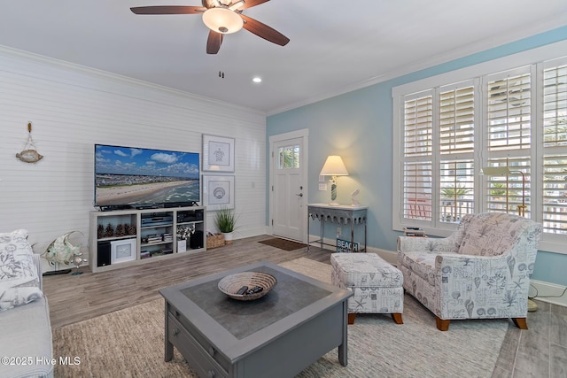 living room featuring ornamental molding, ceiling fan, and light hardwood / wood-style flooring