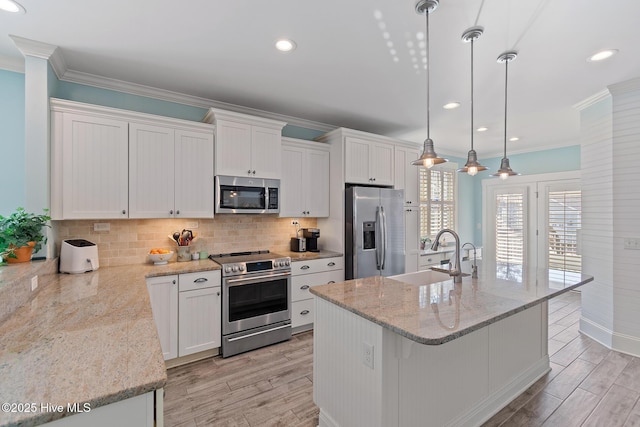 kitchen featuring stainless steel appliances, sink, pendant lighting, and white cabinets