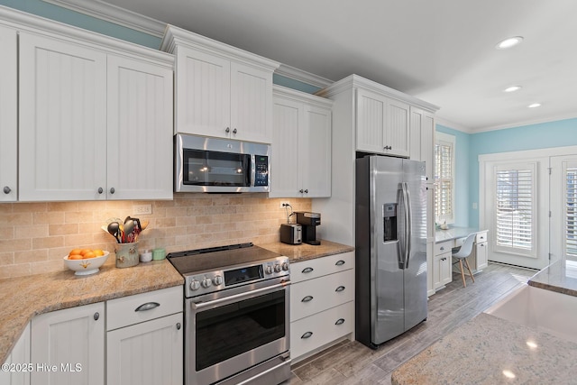 kitchen with crown molding, light stone counters, stainless steel appliances, decorative backsplash, and white cabinets