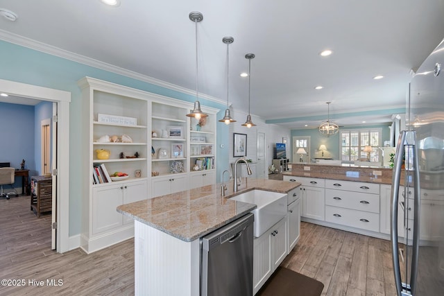 kitchen with decorative light fixtures, white cabinetry, sink, stainless steel appliances, and a center island with sink