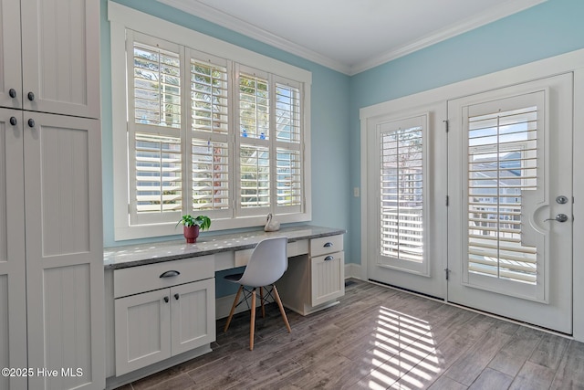 home office featuring crown molding, built in desk, and light hardwood / wood-style flooring