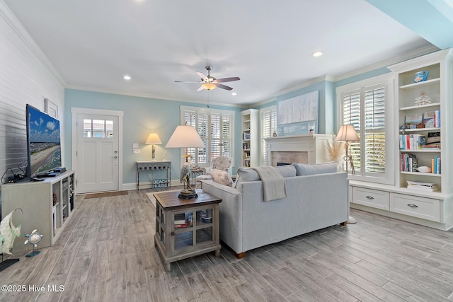 living room with ornamental molding, built in features, ceiling fan, and light hardwood / wood-style floors