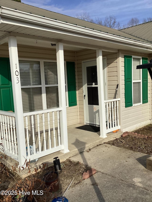 doorway to property featuring covered porch and metal roof