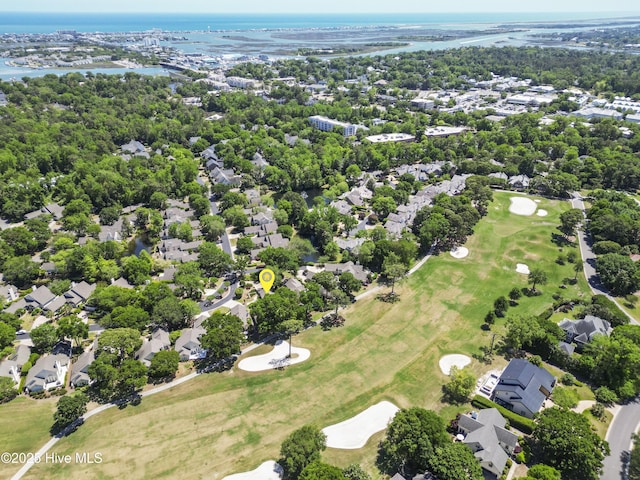 view of property location featuring a nearby body of water, nearby suburban area, a golf club, and a tree filled landscape