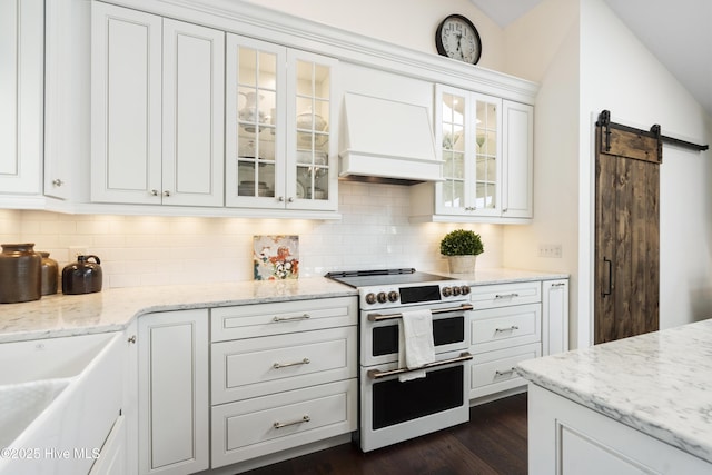 kitchen featuring range with two ovens, custom exhaust hood, a barn door, and backsplash