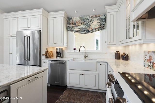 kitchen with stainless steel appliances, a sink, white cabinets, light stone counters, and recessed lighting