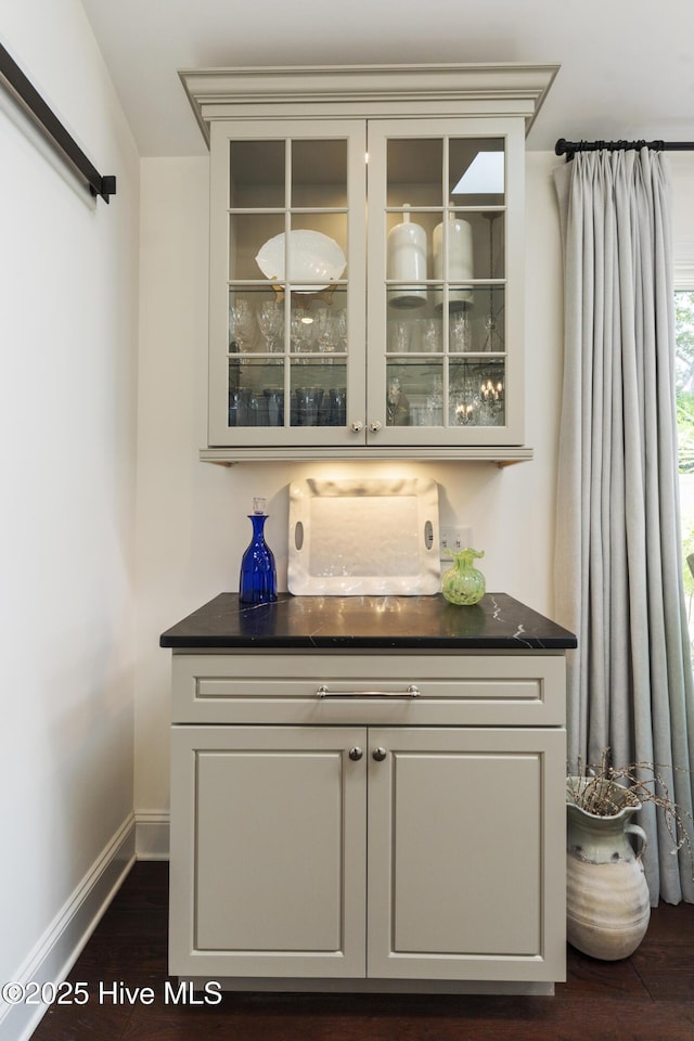 indoor dry bar featuring dark wood-style floors and baseboards