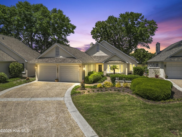 view of front facade featuring stucco siding, a garage, concrete driveway, and a lawn