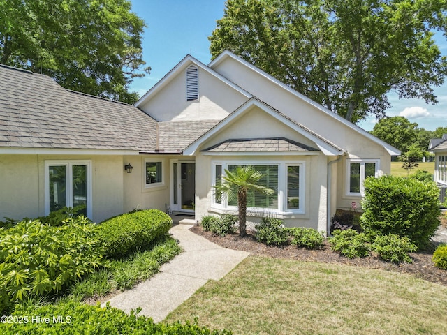 view of front of property featuring stucco siding, a front lawn, and a shingled roof