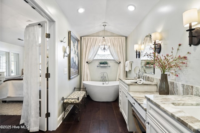 full bath featuring vanity, hardwood / wood-style floors, a soaking tub, ensuite bathroom, and a chandelier