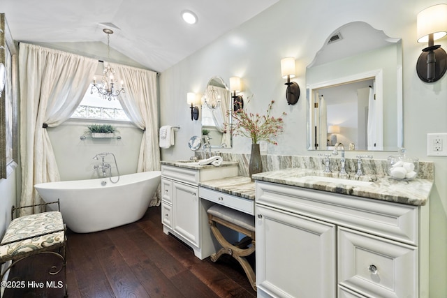 full bath with a chandelier, wood-type flooring, a freestanding bath, vanity, and lofted ceiling