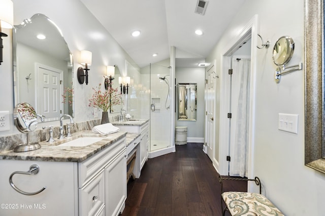 full bath with lofted ceiling, a stall shower, wood finished floors, double vanity, and recessed lighting