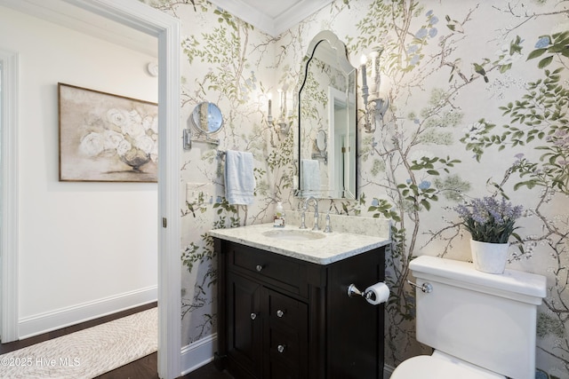 bathroom featuring wallpapered walls, crown molding, toilet, vanity, and baseboards