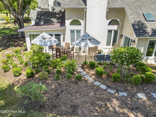 back of house featuring stucco siding, a shingled roof, and outdoor dining area