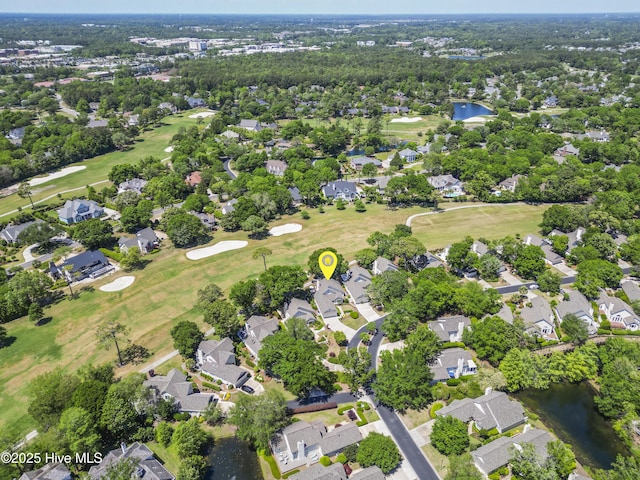 view of property location with a golf club, a nearby body of water, and nearby suburban area