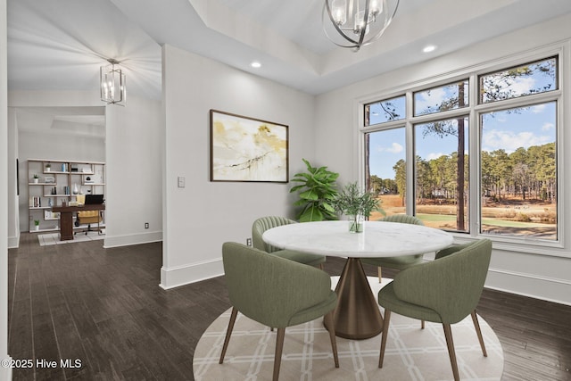 dining area featuring a raised ceiling, dark hardwood / wood-style floors, and a chandelier