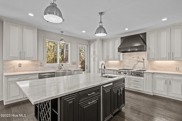 kitchen with sink, custom exhaust hood, an island with sink, and appliances with stainless steel finishes