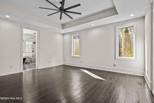 unfurnished room featuring a raised ceiling, dark wood-type flooring, and ceiling fan