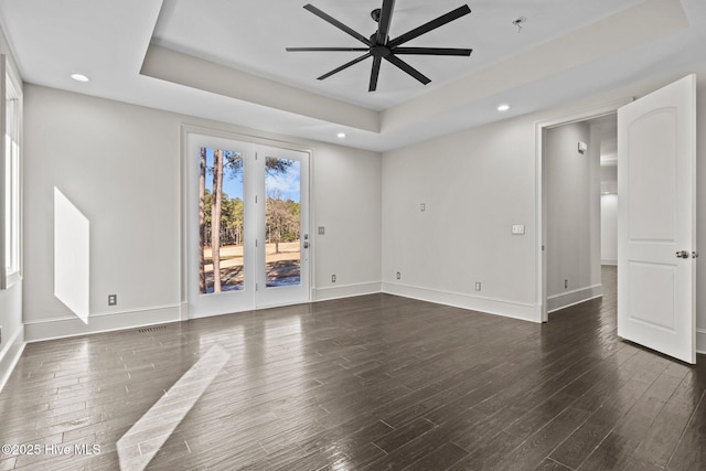 unfurnished room featuring dark hardwood / wood-style floors, a raised ceiling, and ceiling fan