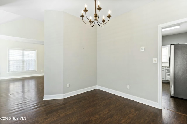 spare room with dark wood-type flooring, lofted ceiling, and an inviting chandelier