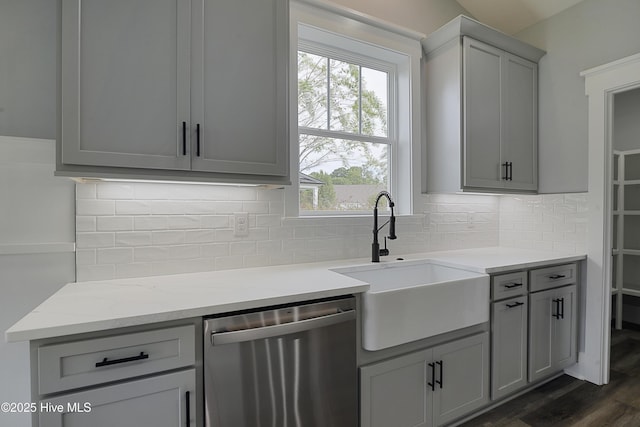 kitchen featuring stainless steel dishwasher, gray cabinets, sink, and backsplash