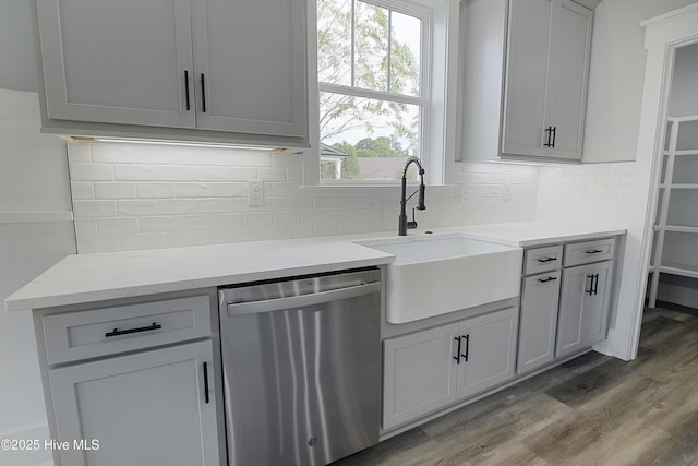 kitchen with sink, dishwasher, gray cabinetry, backsplash, and wood-type flooring