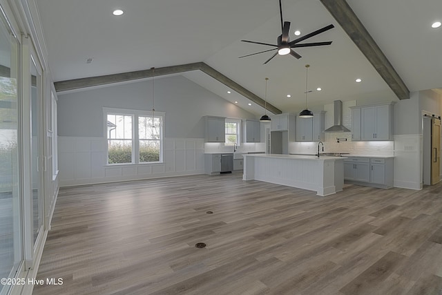 unfurnished living room with vaulted ceiling with beams, wood-type flooring, sink, and ceiling fan