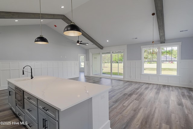 kitchen featuring hanging light fixtures, sink, and an island with sink