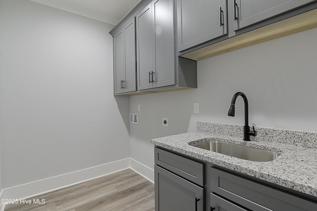 washroom with sink, cabinets, light wood-type flooring, hookup for a washing machine, and hookup for an electric dryer