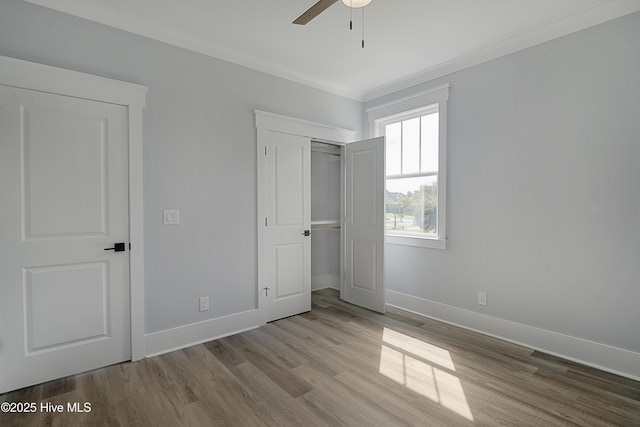 unfurnished bedroom featuring crown molding, ceiling fan, light hardwood / wood-style floors, and a closet