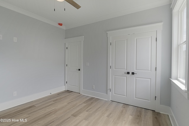 unfurnished bedroom featuring crown molding, light hardwood / wood-style floors, a closet, and ceiling fan