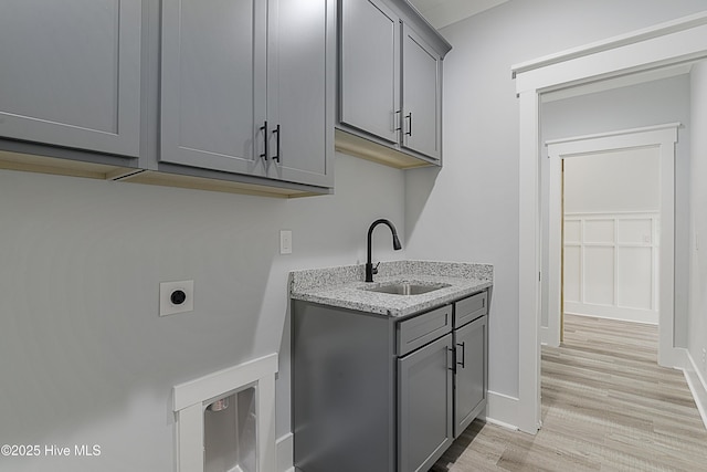 laundry area featuring cabinets, sink, hookup for an electric dryer, and light hardwood / wood-style floors