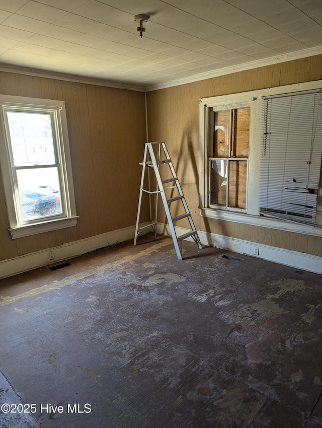 spare room featuring crown molding and wooden walls