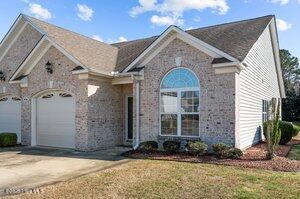 view of front of property featuring a garage, concrete driveway, brick siding, and a front yard