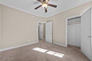 unfurnished bedroom featuring carpet floors, baseboards, ornamental molding, and a closet