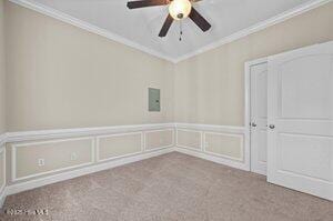 spare room with carpet floors, a wainscoted wall, ornamental molding, and a decorative wall