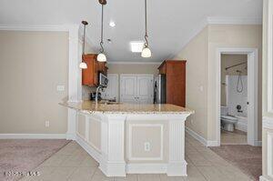 kitchen with a peninsula, a sink, ornamental molding, fridge, and stainless steel microwave