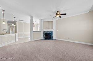 unfurnished living room featuring carpet, a fireplace, baseboards, and ceiling fan