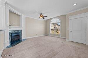 unfurnished living room featuring ceiling fan, crown molding, a fireplace, and baseboards