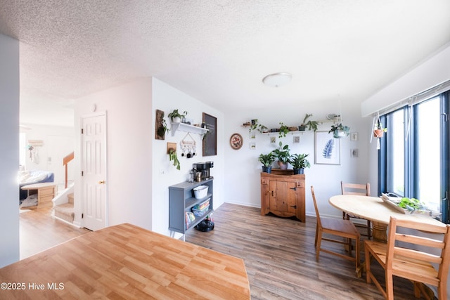 dining room with wood-type flooring and a textured ceiling