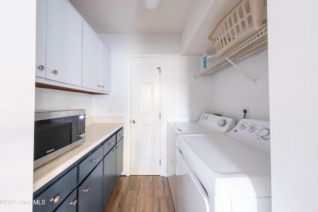 clothes washing area with dark wood-type flooring, cabinets, separate washer and dryer, and a textured ceiling