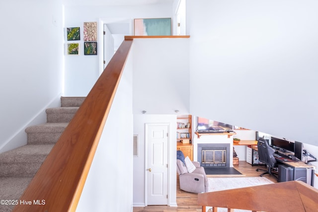 stairs with hardwood / wood-style floors and a high ceiling