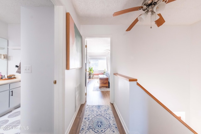 hallway with a textured ceiling and light wood-type flooring