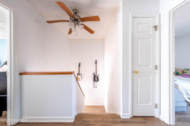 staircase with hardwood / wood-style flooring, ceiling fan, and a textured ceiling