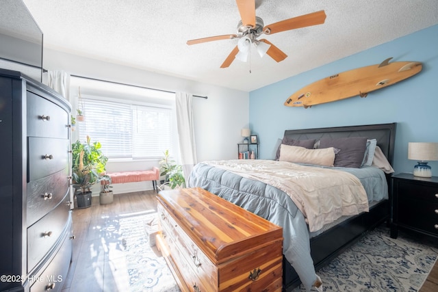 bedroom with ceiling fan, wood-type flooring, and a textured ceiling