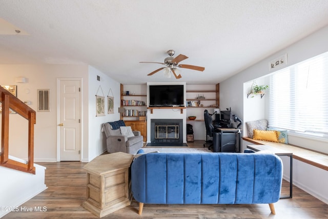 living room with hardwood / wood-style flooring, a textured ceiling, and ceiling fan