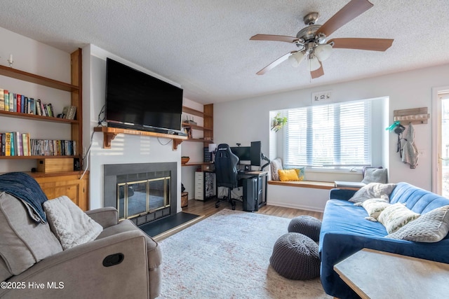 living room featuring ceiling fan, light hardwood / wood-style flooring, and a textured ceiling