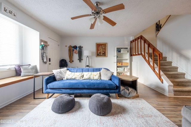 living room featuring hardwood / wood-style flooring, ceiling fan, and a textured ceiling