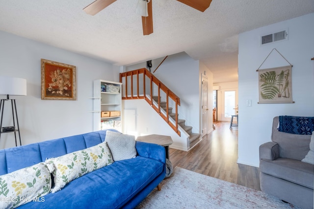 living room with ceiling fan, wood-type flooring, and a textured ceiling